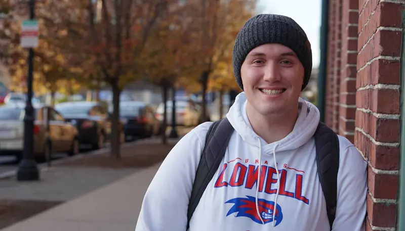 Tom Stranberg poses outdoors wearing a UMass Lowell sweatshirt