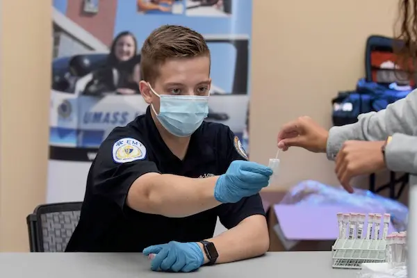 A student EMT takes a testing swab from a student