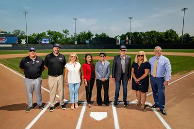 Image shows leaders from the city of Lowell, state, Futures Collegiate Baseball Leage and UMass Lowell on the playing diamond of LeLacheur Park in Lowell
