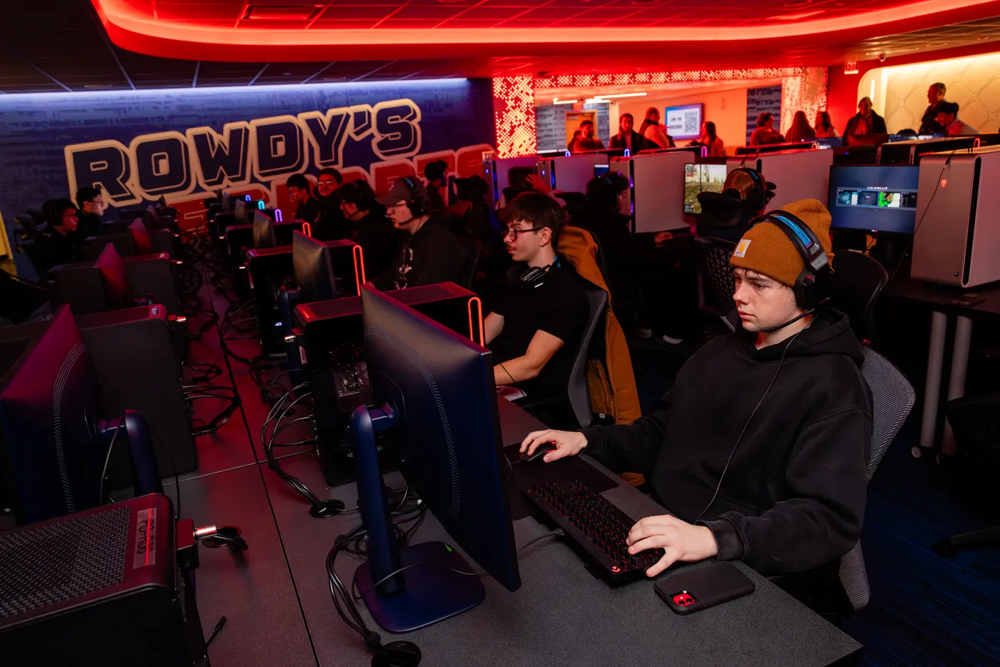 College students sit at a row of computes and play video games in an esports arena.