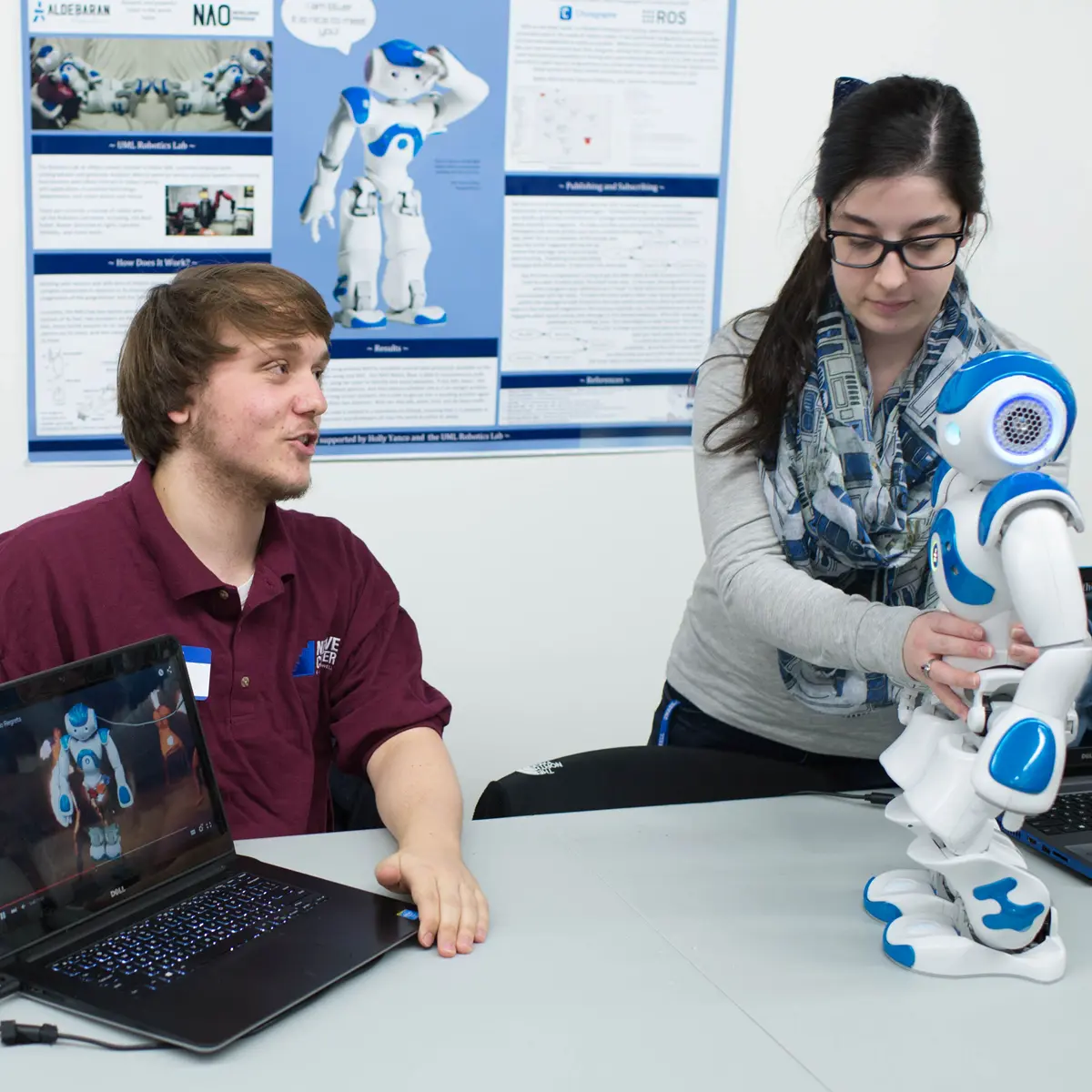 Two students work with a robot and laptop in the NERVE Center at UMass Lowell.