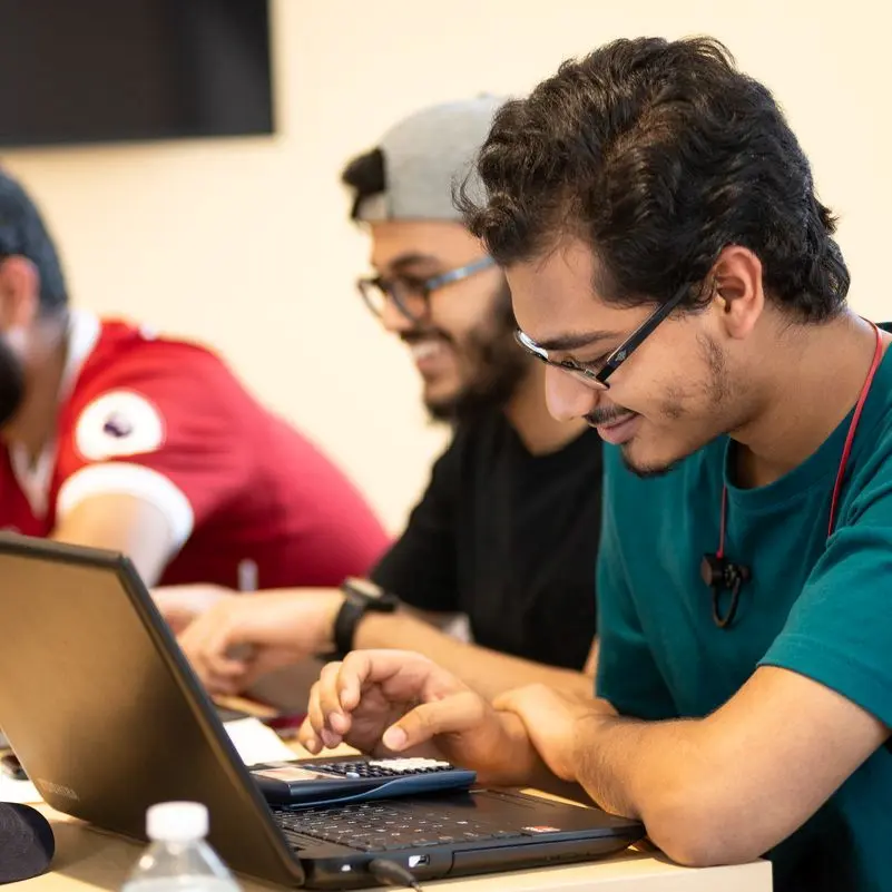 Student uses a calculator while working on a laptop in a UMass Lowell computer science classroom.
