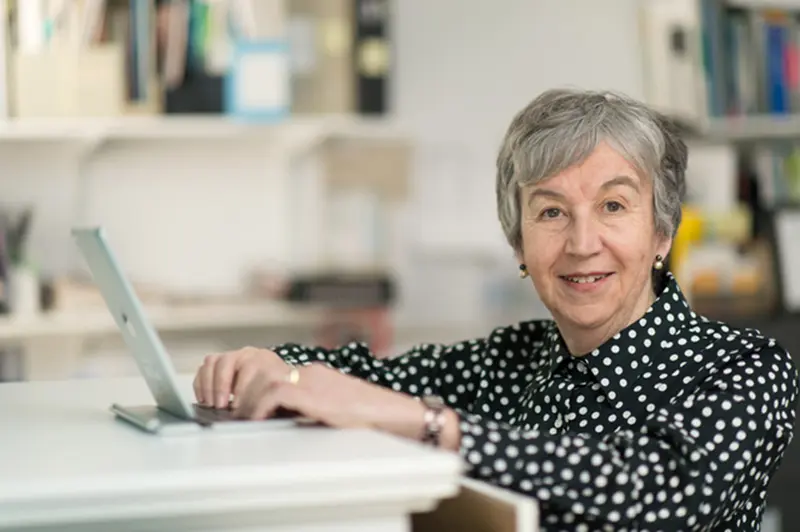 Diane Feeney Mahoney works at a laptop at a desk in a bright, white office
