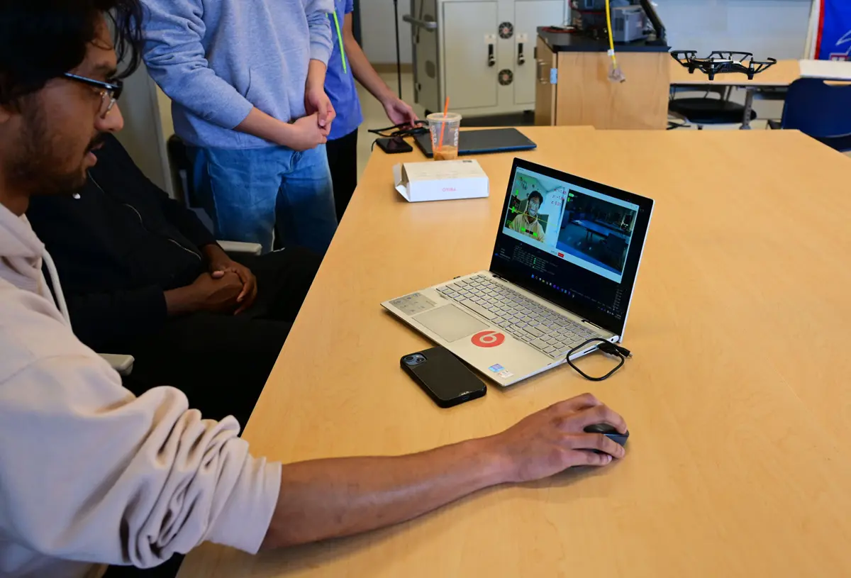 A capstone project team using a laptop with facial recognition software.