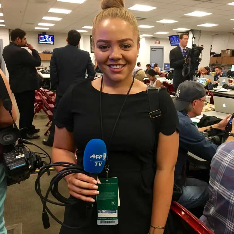 Student holds a microphone inside a newsroom.