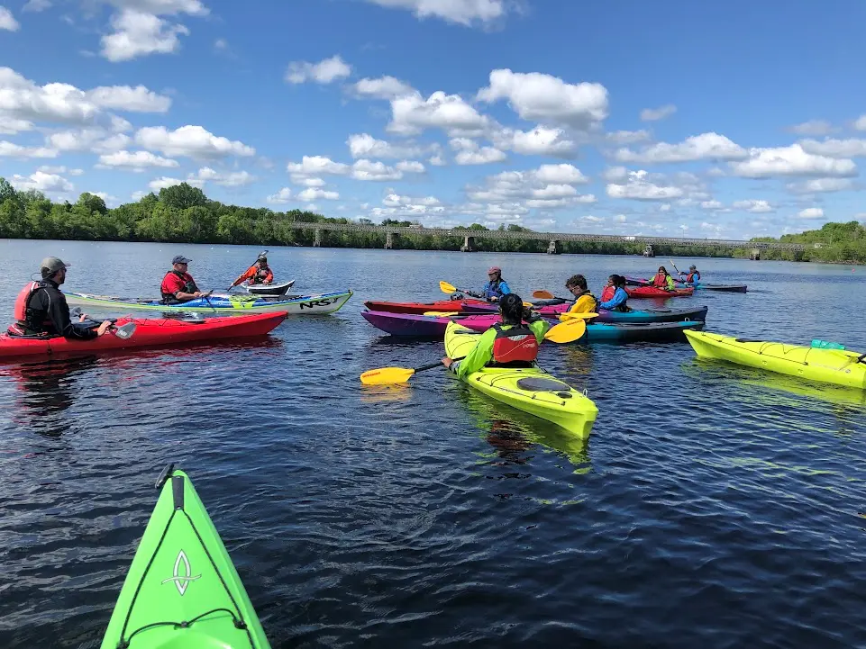 group floats in single kayaks together on a blue sky day with white fluffy clouds