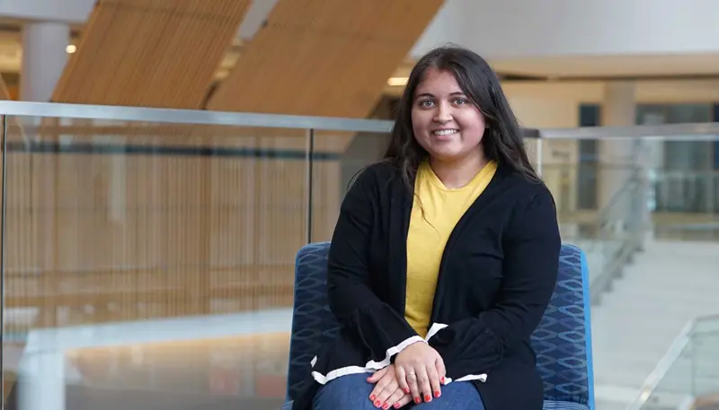 Finance student Heer Patel seated inside a UMass Lowell building
