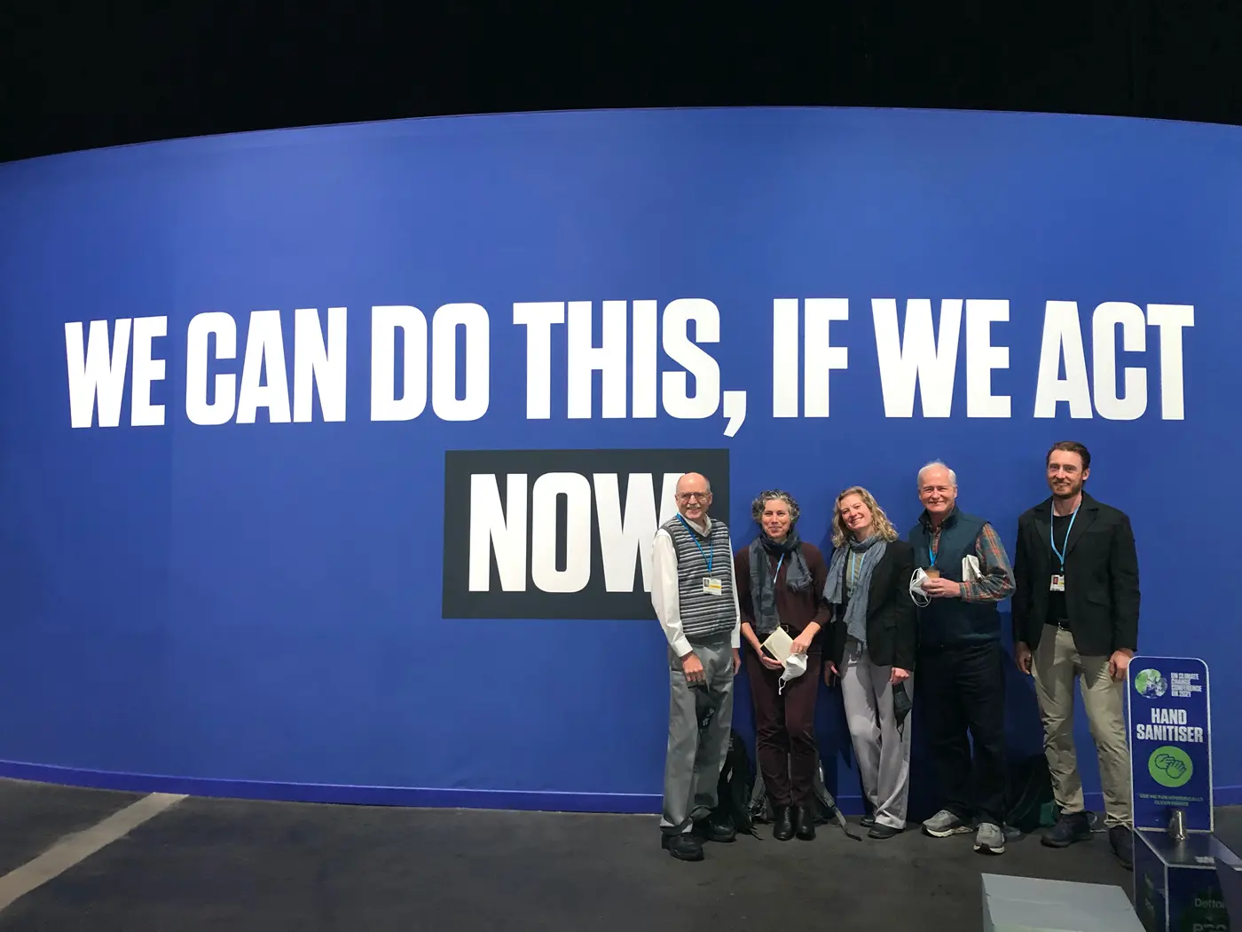 Juliette Rooney-Varga and friends in front of We Can Do This is We Act NOW sign