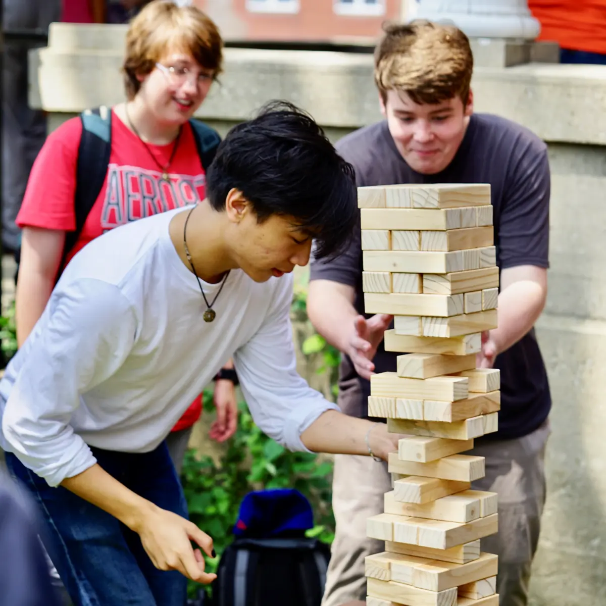 Three male students play giant Jenga