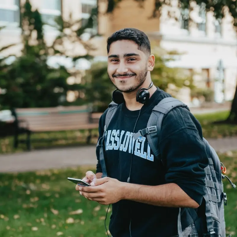 Student with UMass Lowell shirt and headphones around their neck.