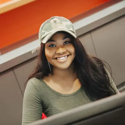 female student with baseball cap smiling 