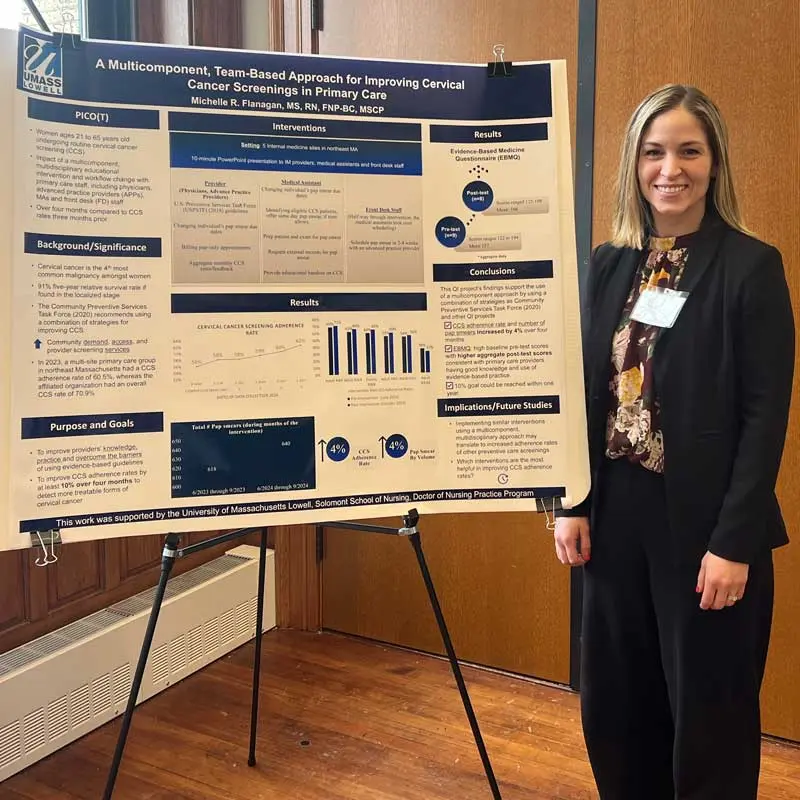 A UMass Lowell nuring student stands next to her research poster titled, "A Multicomponent, Team-Based Approach for Improving Cervical Cancer Screenings in Primary Care."
