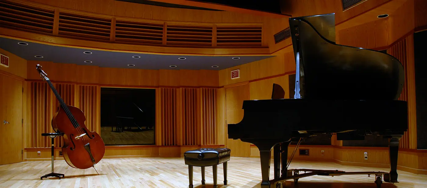 A piano and bass sitting in Room 114 s studio of the Sound Recording Technology program. 