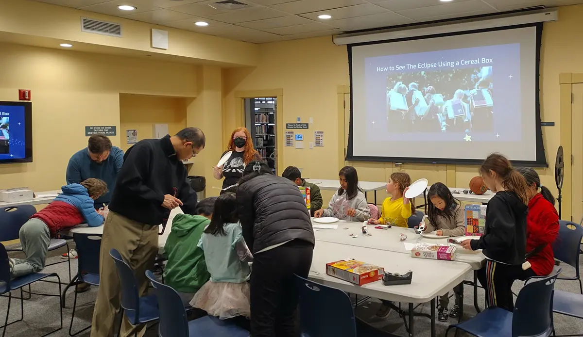 Julie Sage and LoCSST student volunteers helping kids build a device to view eclipse using a cereal box