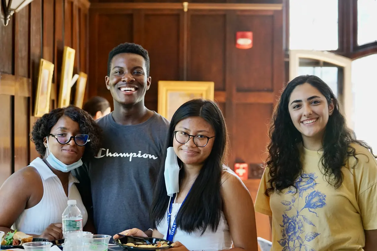 Four students, three females and a male, smile