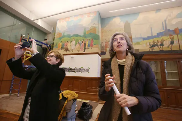Chancellor Jacqueline Moloney and Art professor Marie Frank look at the relief sculptures in the large hall of Coburn Hall