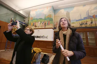Chancellor Jacqueline Moloney and Art professor Marie Frank look at the relief sculptures in the large hall of Coburn Hall