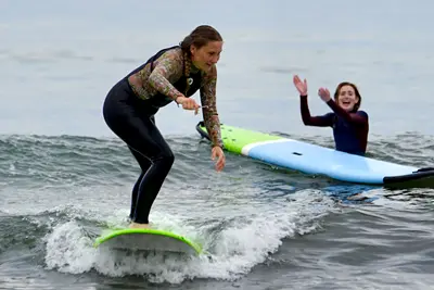 Ten people stand in a line holding surfboards behind them while standing on an ocean beach.