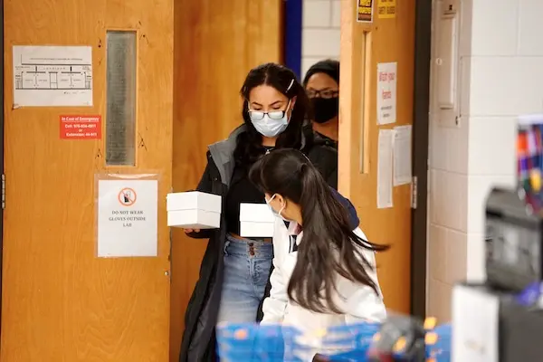 A student delivers boxes with covid test swabs to the lab