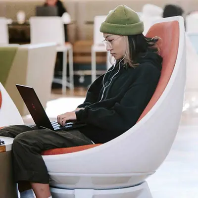 Student sitting in a chair while working on a laptop