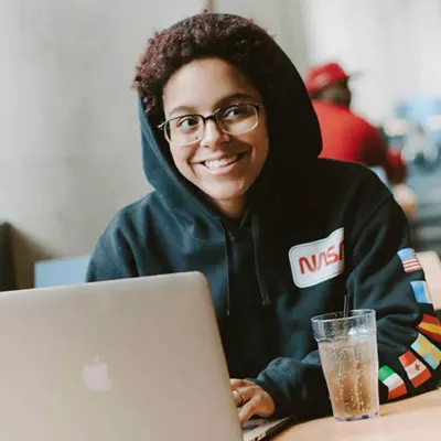 Student smiling while working on a laptop