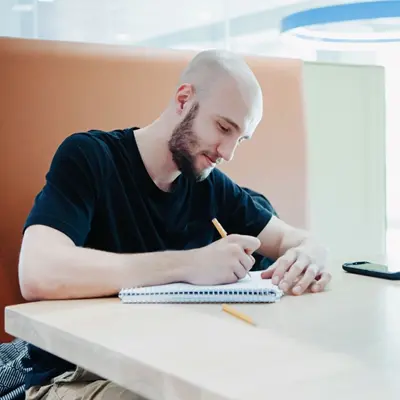 white male student writing in notebook