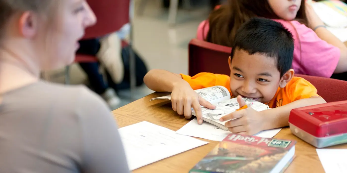 Smiling young boy at Bartlett School with book in front of him 